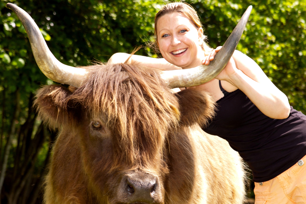Young pretty woman hugs an highland cattle
